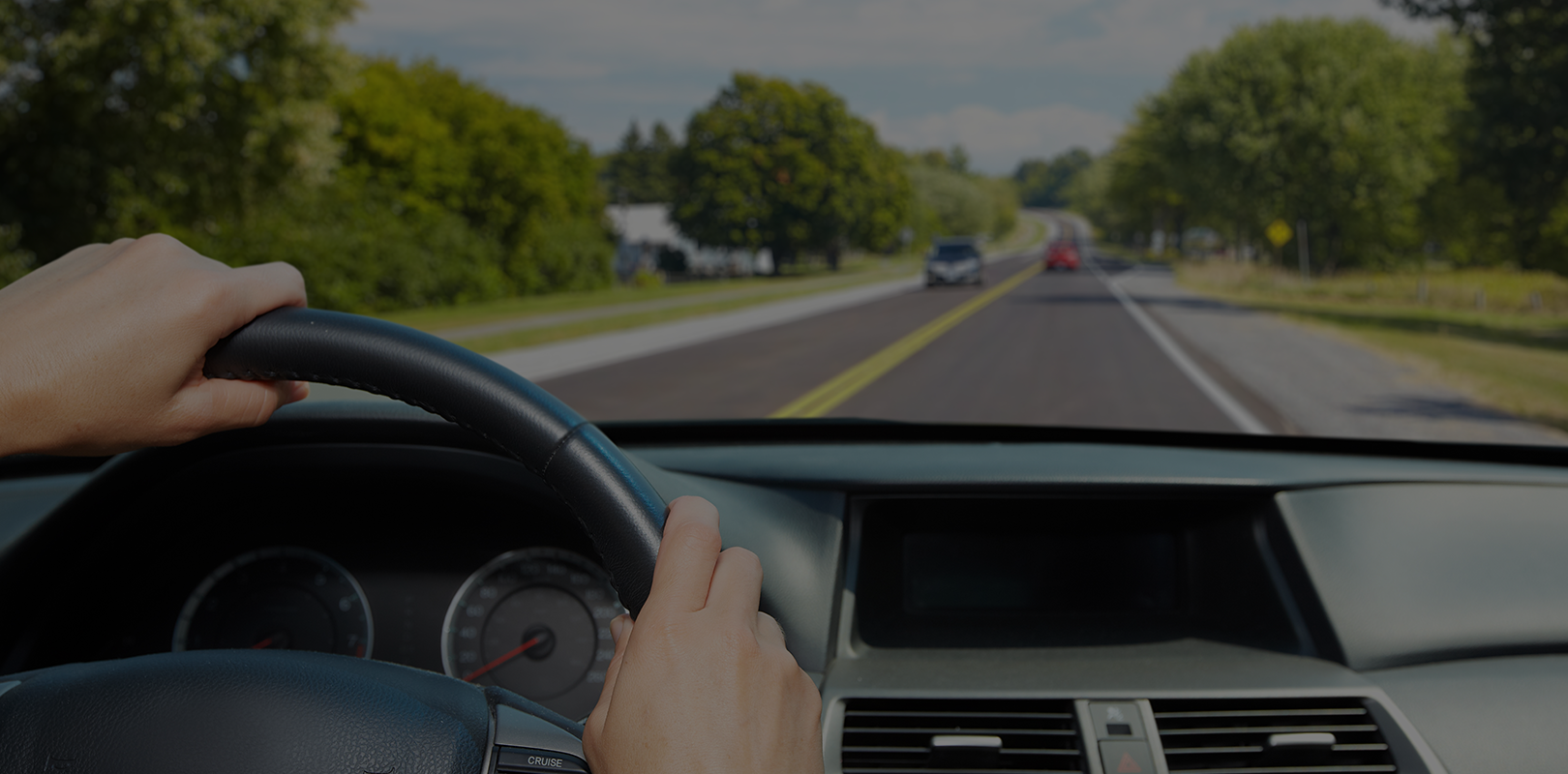 Driver holding steering wheel on a sunny highway.